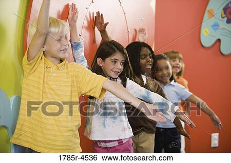 Boys and girls posing and leaning against a colorful wall View Large Photo Image Stock Photograph - Boys and girls posing and leaning against a colorful wall. Fotosearch