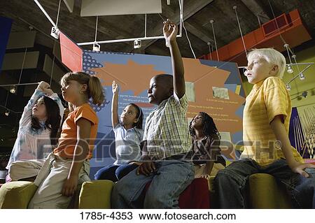 Stock Image - Boys and girls watching and listening attentively in class. Fotosearch