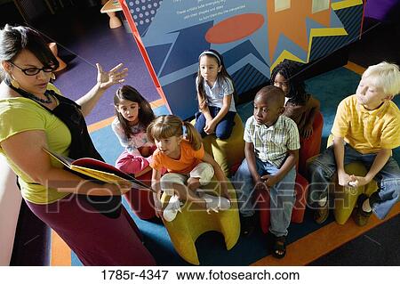 Stock Photo - Boys and girls watching and listening attentively to their teacher. Fotosearch