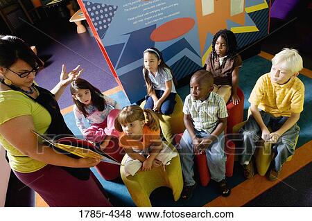 Stock Photo - Boys and girls watching and listening attentively to their teacher. Fotosearch