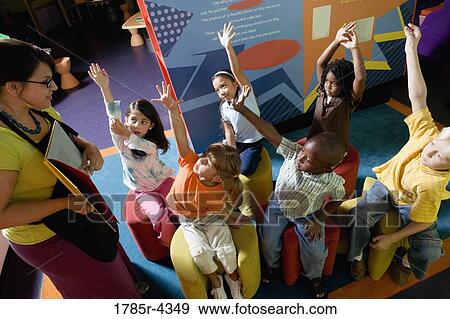 Stock Photo - Boys and girls watching and listening attentively to their teacher. Fotosearch