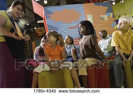 Stock Photography - Boys and girls watching and listening attentively to their teacher. Fotosearch