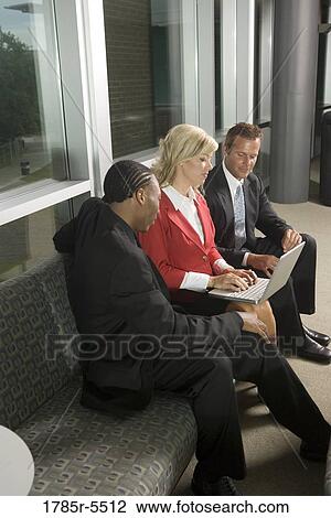 Stock Image - Business executives working together on laptop. Fotosearch