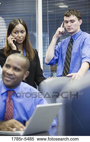 Business man and woman using mobile phone while colleague uses laptop computer in foreground View Large Photo Image Stock Photography - Business man and woman using mobile phone while colleague uses laptop computer in foreground. Fotosearch