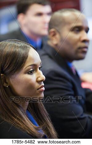Business men and women watching and listening attentively in a meeting View Large Photo Image Stock Image - Business men and women watching and listening attentively in a meeting. Fotosearch