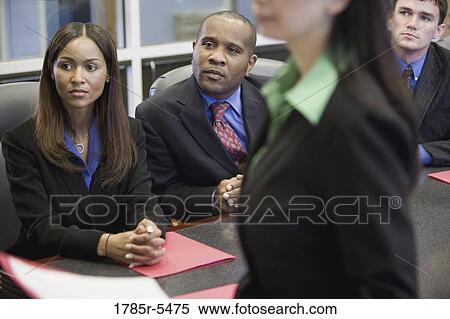 Business men and women watching and listening attentively in a meeting View Large Photo Image Stock Photography - Business men and women watching and listening attentively in a meeting. Fotosearch