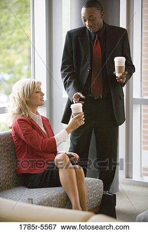 Business people sitting an waiting in an office lobby, holding coffee cups View Large Photo Image Stock Photo - Business people sitting an waiting in an office lobby, holding coffee cups. Fotosearch