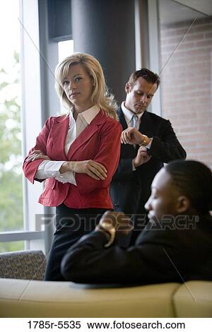 Business people sitting and waiting in an office lobby, looking at their watches View Large Photo Image Stock Photography - Business people sitting and waiting in an office lobby, looking at their watches. Fotosearch