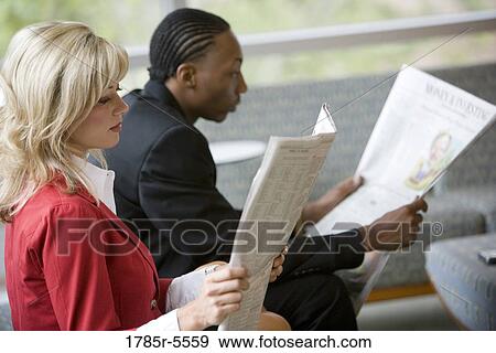 Business people sitting in an office lobby reading newspapers View Large Photo Image Stock Photo - Business people sitting in an office lobby reading newspapers. Fotosearch