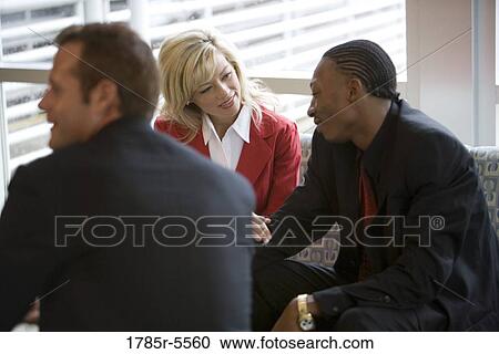 Stock Image - Business people sittingin an office lobby and ocnversing. Fotosearch