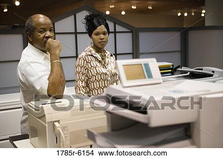 Business people standing next to office equipment View Large Photo Image Picture - Business people standing next to office equipment. Fotosearch