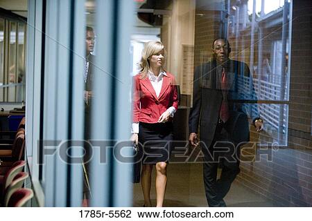 Business people walking and conversing in an office hallway View Large Photo Image Stock Image - Business people walking and conversing in an office hallway. Fotosearch