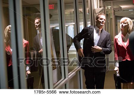 Stock Photograph - Business people walking and conversing in an office hallway. Fotosearch