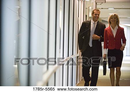 Business people walking and conversing in an office hallway View Large Photo Image Stock Photography - Business people walking and conversing in an office hallway. Fotosearch