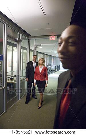 Business people walking down office hallway and lobby and conversing View Large Photo Image Stock Image - Business people walking down office hallway and lobby and conversing. Fotosearch