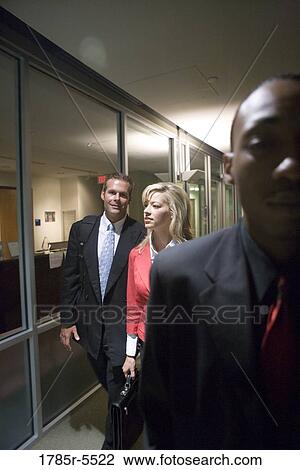 Stock Image - Business people walking down office hallway and lobby and conversing. Fotosearch
