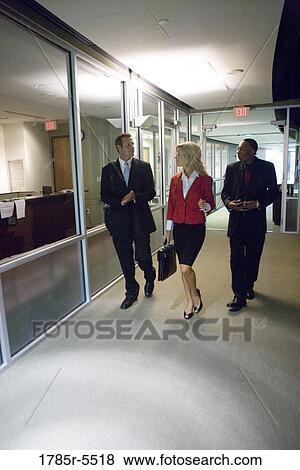 Stock Photo - Business people walking down office hallway and lobby and conversing. Fotosearch