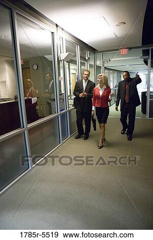 Business people walking down office hallway and lobby and conversing View Large Photo Image Stock Photo - Business people walking down office hallway and lobby and conversing. Fotosearch