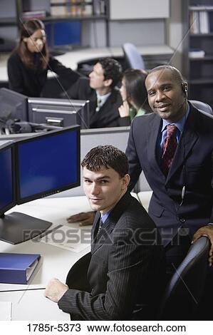 Stock Image - Business people working in a busy office. Fotosearch