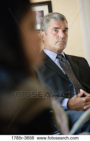 Businessman and woman sitting in office View Large Photo Image Stock Photograph - Businessman and woman sitting in office. Fotosearch