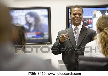 Businessman conversing with colleagues in office View Large Photo Image Stock Image - Businessman conversing with colleagues in office. Fotosearch