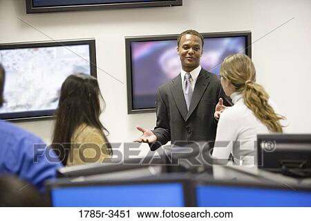 Businessman conversing with colleagues in office View Large Photo Image Stock Image - Businessman conversing with colleagues in office. Fotosearch