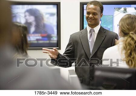Businessman conversing with colleagues in office View Large Photo Image Stock Photo - Businessman conversing with colleagues in office. Fotosearch