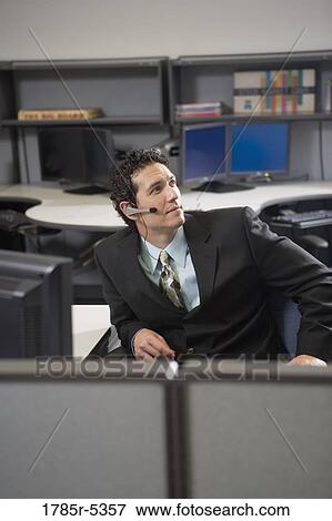 Businessman in a suit with headset sitting in an office View Large Photo Image Stock Photo - Businessman in a suit with headset sitting in an office. Fotosearch