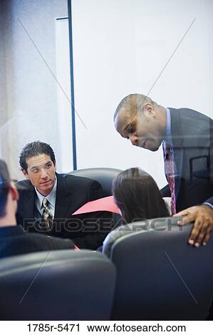 Businessman paying attention to one of his colleagues while others watch View Large Photo Image Stock Image - Businessman paying attention to one of his colleagues while others watch. Fotosearch