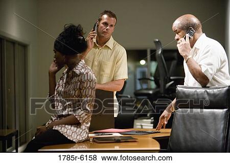 Stock Photo - Businesspeople using mobile phones in office. Fotosearch