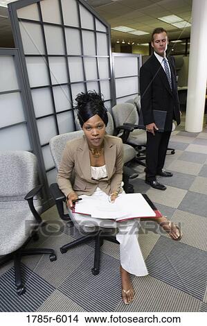 Picture - Businesswoman looking into a folder while man looks over her shoulder. Fotosearch
