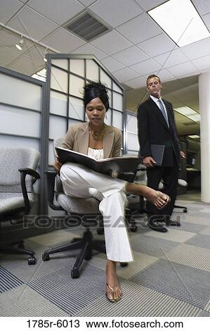 Businesswoman looking into a folder while man looks over her shoulder View Large Photo Image Stock Image - Businesswoman looking into a folder while man looks over her shoulder. Fotosearch