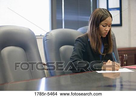 Businesswoman writing while seated at a conference table View Large Photo Image Picture - Businesswoman writing while seated at a conference table. Fotosearch