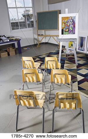 Stock Image - Chairs in an art class facing an easel. Fotosearch