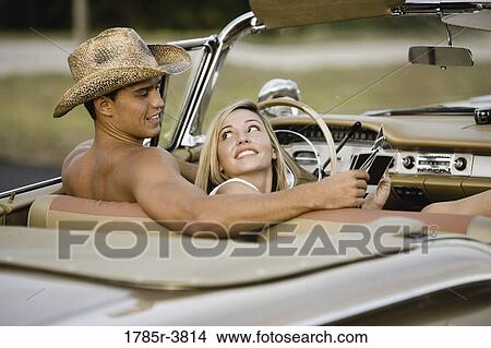 Cheerful and playful couple sitting in antique convertible car View Large Photo Image Picture - Cheerful and playful couple sitting in antique convertible car. Fotosearch