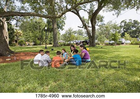 Children and their teacher sitting in a circle on the grass at a park View Large Photo Image Stock Image - Children and their teacher sitting in a circle on the grass at a park. Fotosearch
