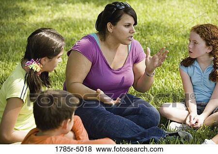 Children and their teacher sitting in a circle on the grass at a park View Large Photo Image Stock Photo - Children and their teacher sitting in a circle on the grass at a park. Fotosearch