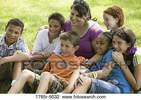 Children and their teacher sitting on the grass at a park watching View Large Photo Image Stock Image - Children and their teacher sitting on the grass at a park watching. Fotosearch