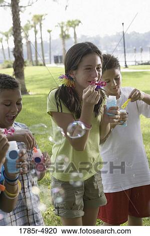 Children blowing bubbles at a park View Large Photo Image Stock Image - Children blowing bubbles at a park. Fotosearch
