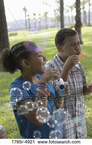 Stock Image - Children blowing bubbles at a park. Fotosearch