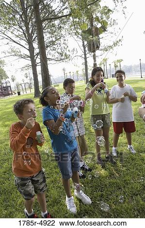 Children blowing bubbles at a park View Large Photo Image Stock Image - Children blowing bubbles at a park. Fotosearch