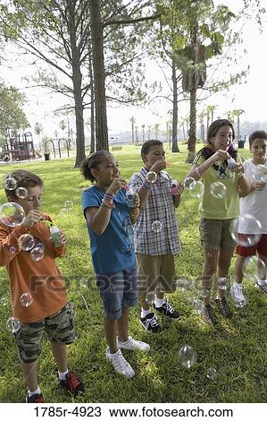Children blowing bubbles at a park View Large Photo Image Stock Image - Children blowing bubbles at a park. Fotosearch