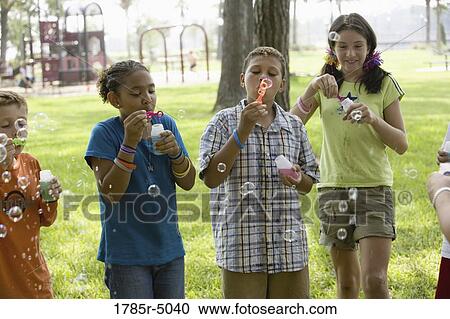 Children blowing bubbles at a park View Large Photo Image Stock Image - Children blowing bubbles at a park. Fotosearch