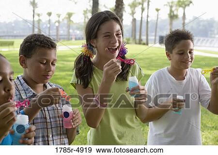 Stock Photo - Children blowing bubbles at a park. Fotosearch