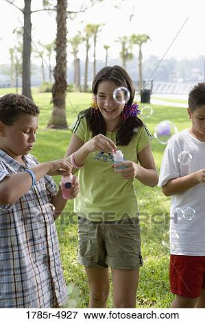 Children blowing bubbles at a park View Large Photo Image Stock Photo - Children blowing bubbles at a park. Fotosearch