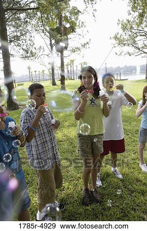 Stock Photo - Children blowing bubbles at a park. Fotosearch