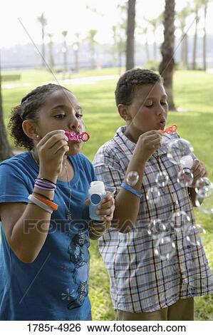 Children blowing bubbles at a park View Large Photo Image Stock Photograph - Children blowing bubbles at a park. Fotosearch