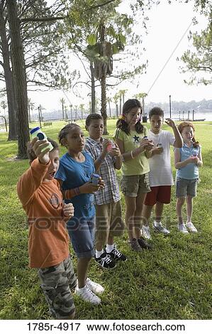 Stock Photo - Children holding bubble bottles at a park. Fotosearch