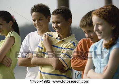 Stock Image - Children outdoors standing side by side. Fotosearch