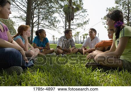 Children sitting in a circle on the grass with their teacher at a park View Large Photo Image Stock Photo - Children sitting in a circle on the grass with their teacher at a park. Fotosearch